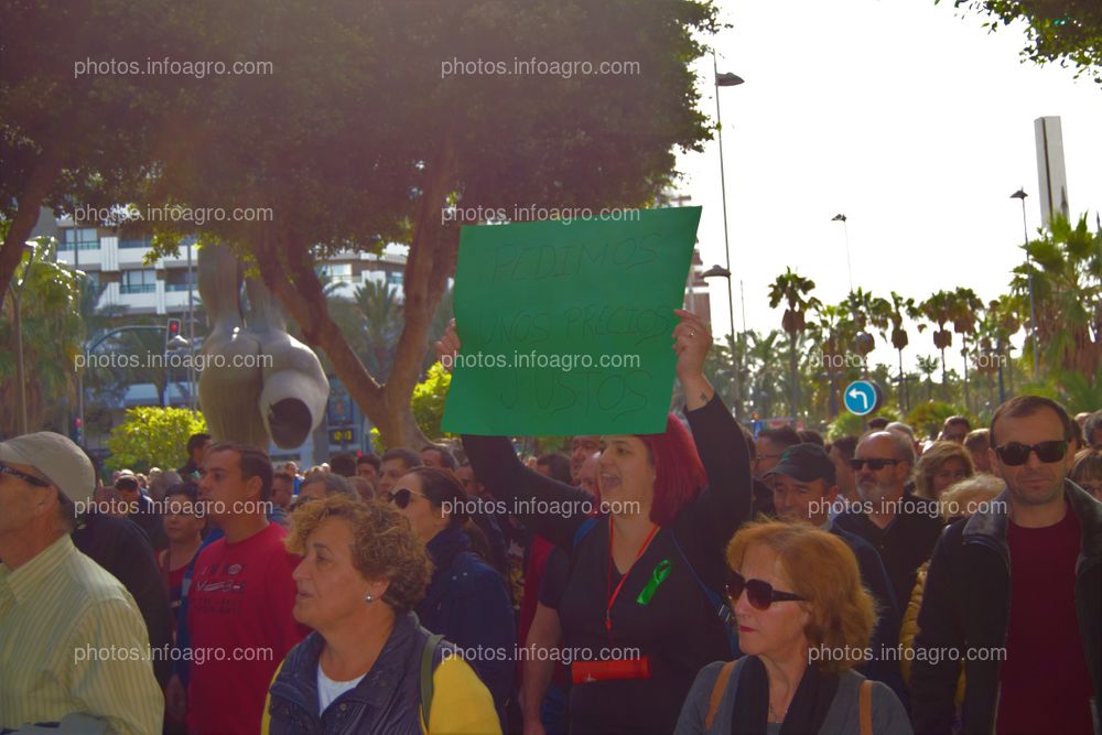 Una manifestante, mostrando una pancarta en la que pide 'Precios justos'