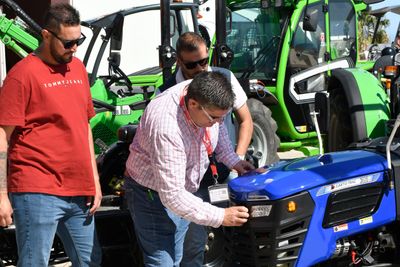 Visitantes profesionales consultan a un expositor sobre uno de sus tractores, en Infoagro Exhibition 2025