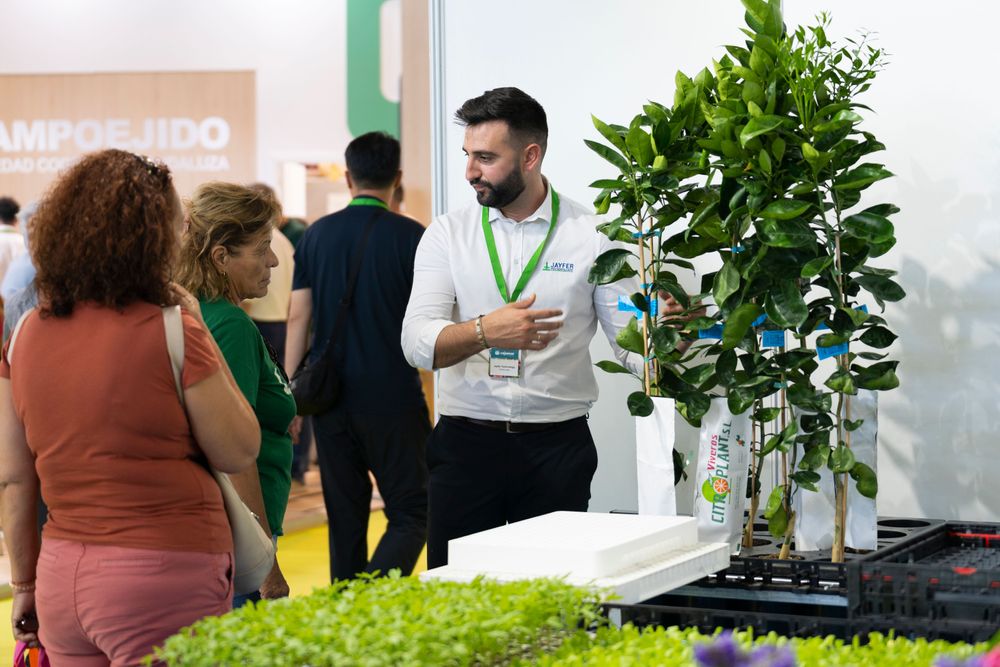 Expositor en Infoagro Exhibition 2025, explicando a dos visitantes profesionales sus productos y servicios
