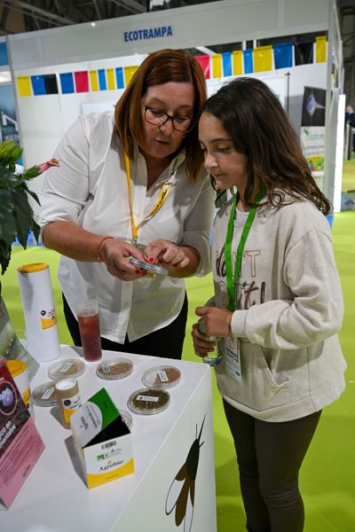 Expositora, mostrando a una estudiante las características de uno de sus productos