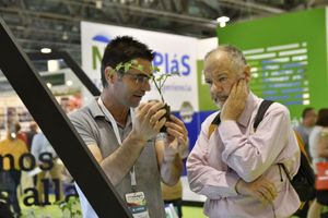 Un miembro del equipo de una empresa expositora en Infoagro Exhibition explica sus productos a un visitante profesional